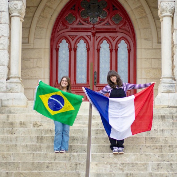 Two women hold flags on the steps of a university building