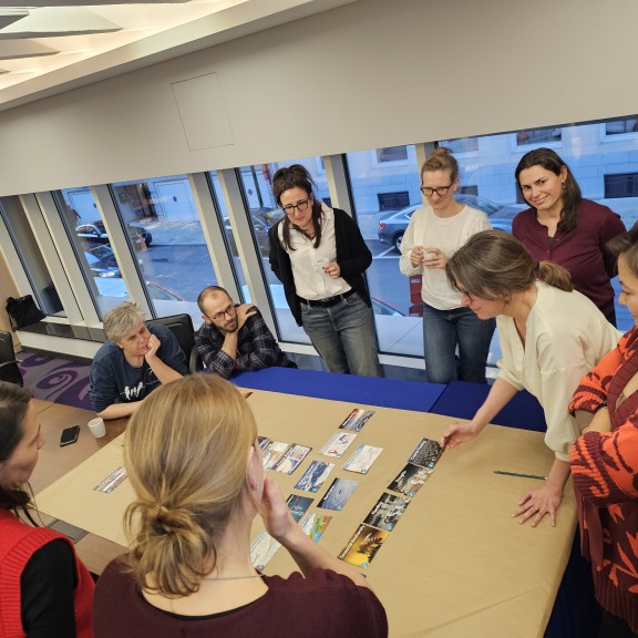 People participating in a workshop gather around a table to discuss