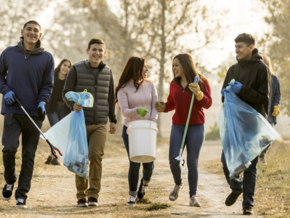 Young adults pick up trash in a park