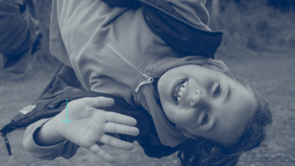 A chid hangs upside down on a playground