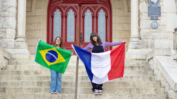 Two women hold flags on the steps of a university building