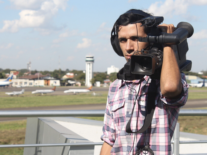 A man holds camera equipment on his shoulder