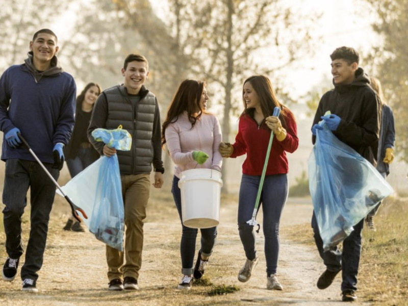 Young adults pick up trash in a park