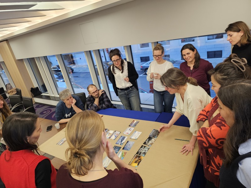 People participating in a workshop gather around a table to discuss