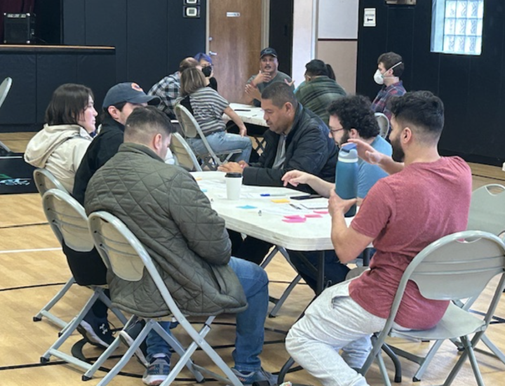 People gather around plastic tables